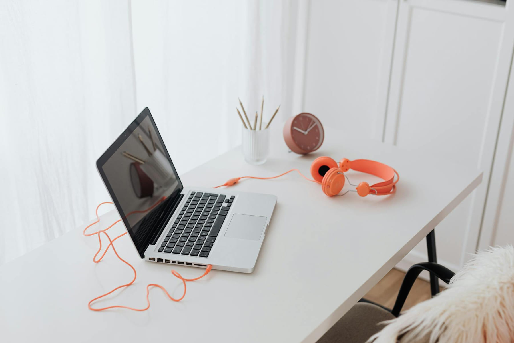 Minimalist workspace featuring a laptop and orange headphones on a clean white desk. on The Digital Hustler