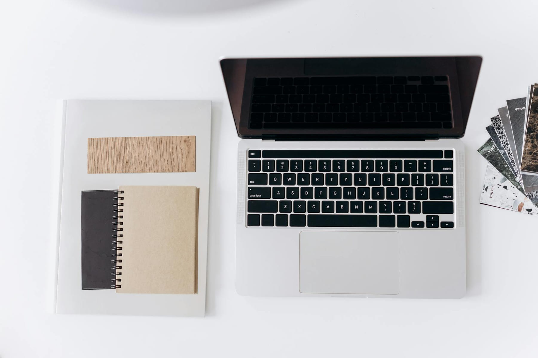 Minimalist workspace setup featuring a laptop, notebooks, and design samples for productivity on The Digital Hustler