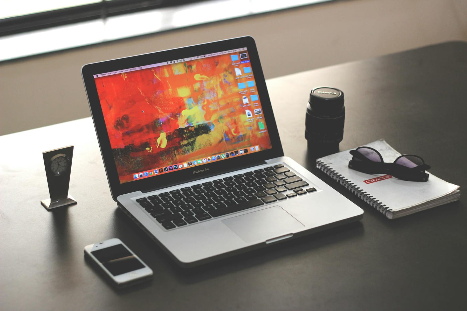 A clean, organized workspace featuring a MacBook, smartphone, and notebook. on The Digital Hustler