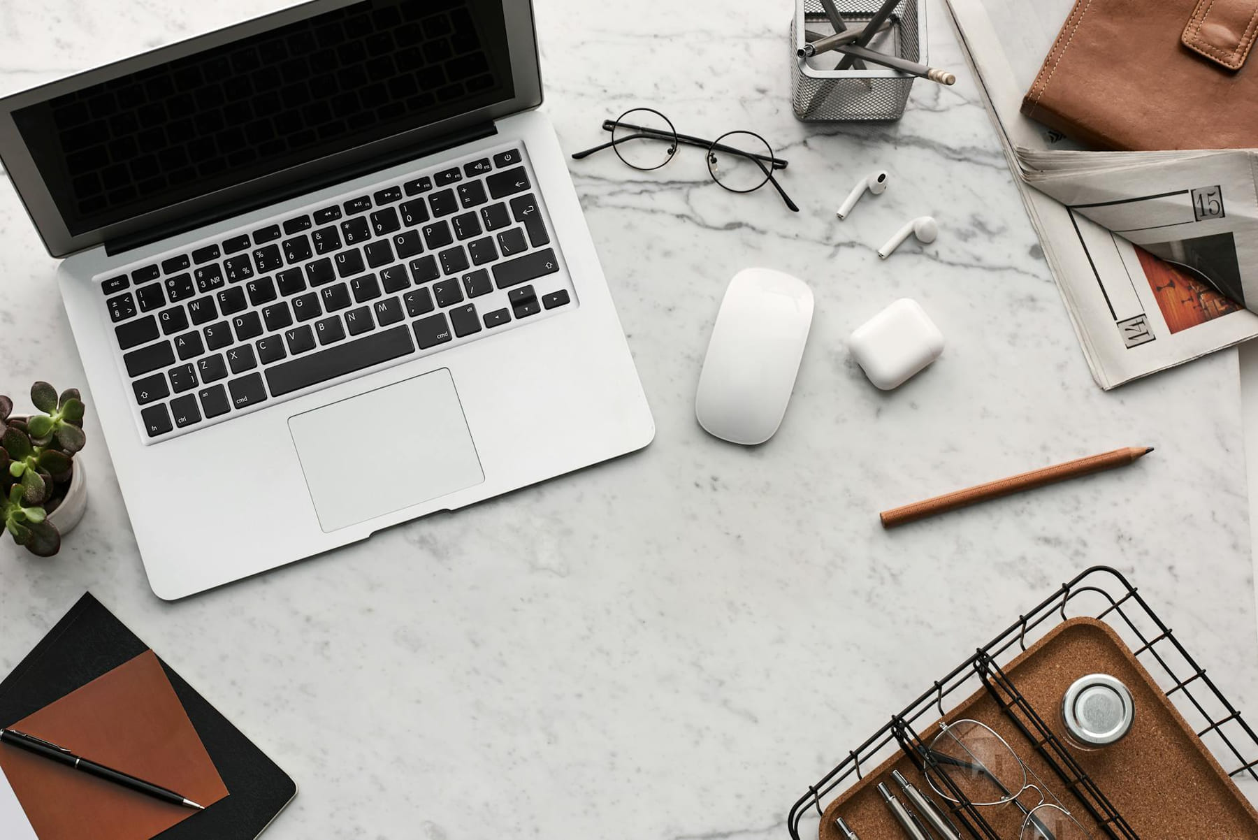 Discover a clean, organized workspace featuring a laptop, AirPods, and stationery essentials on a marble desk. on The Digital Hustler