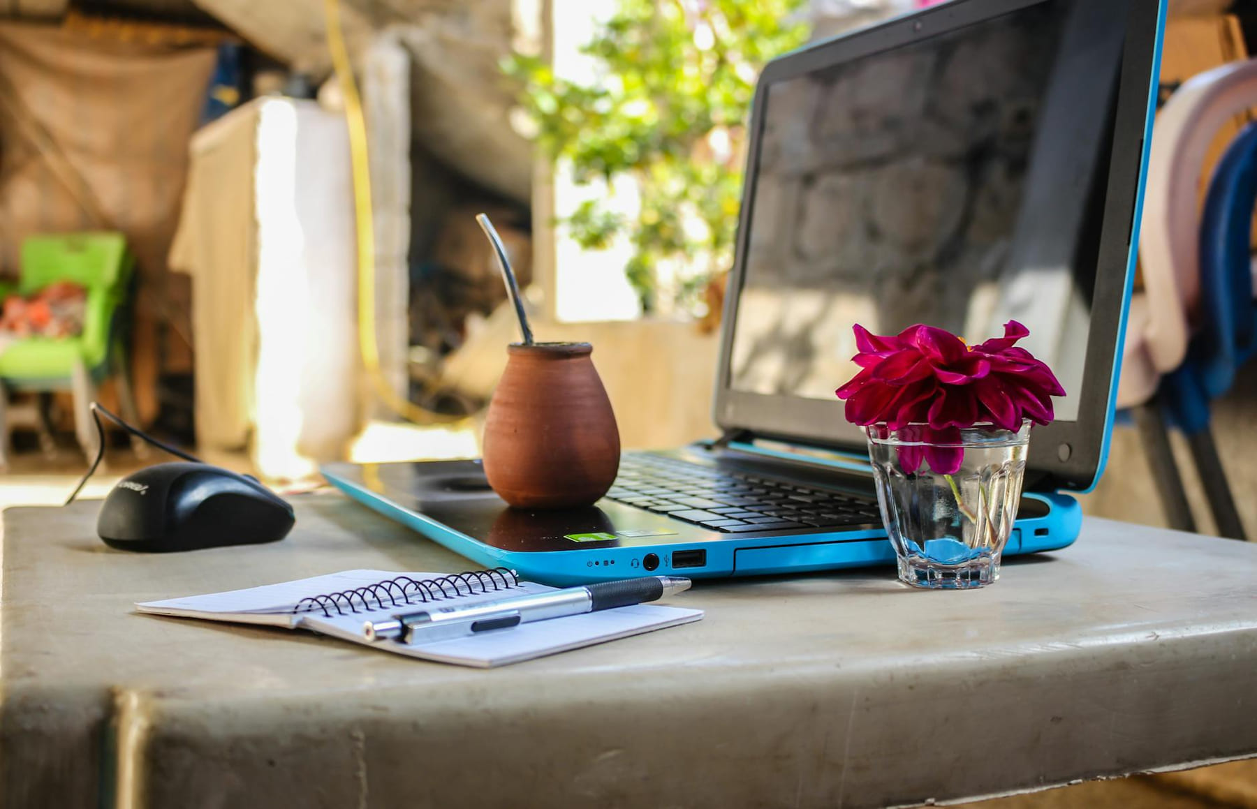 A serene outdoor workspace featuring a laptop, notebook, mug, and flowers on a desk. on The Digital Hustler