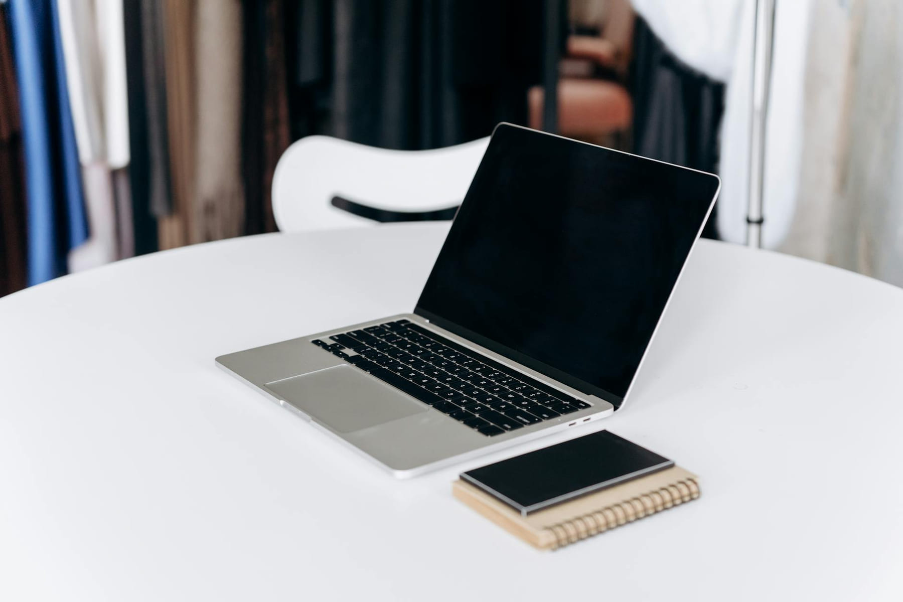 Open laptop and notebook on a stylish white table in an office setting. on The Digital Hustler